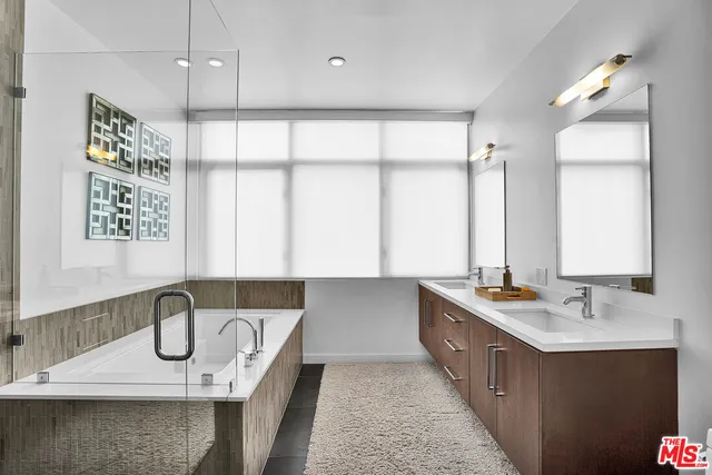 a bathroom with a double vanity sink a mirror and a bathtub