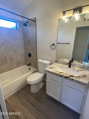 a bathroom with a granite countertop sink toilet a mirror and bathtub