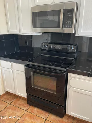 a kitchen with granite countertop white cabinets appliances and a sink