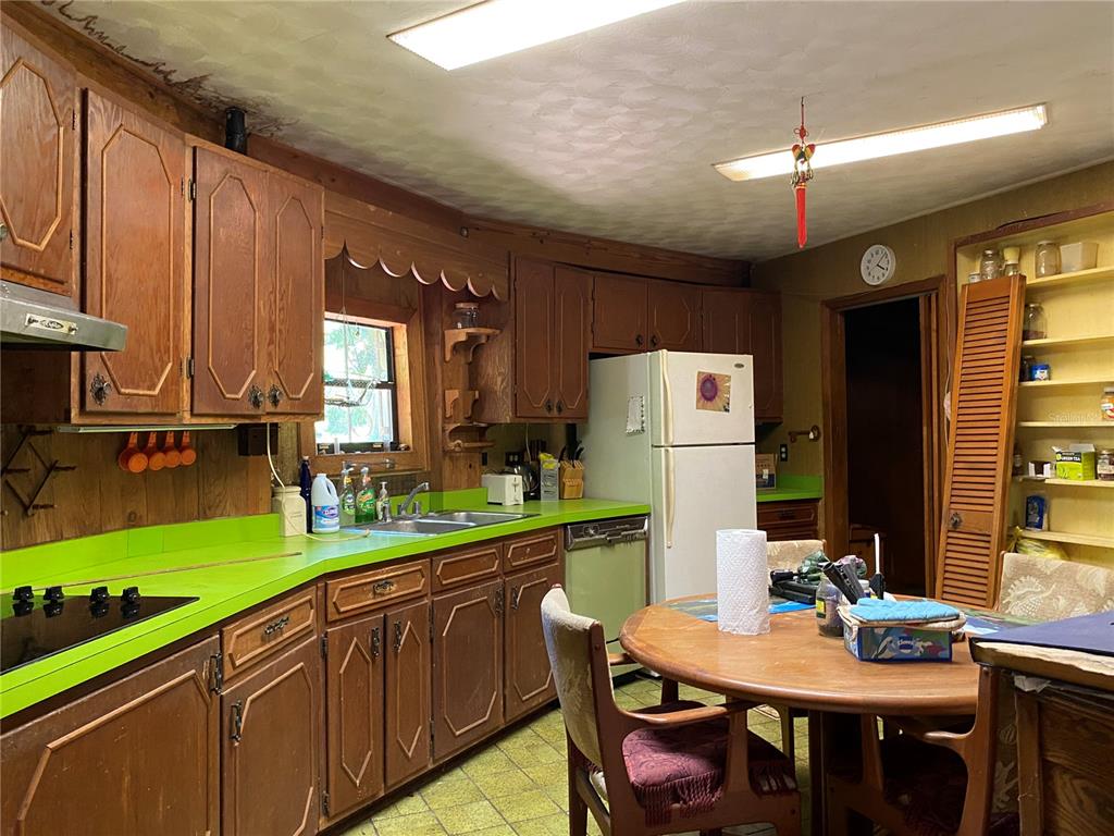 2424 Northeast 170th Street Citra, FL 32113 - Photo 7 of 53 a kitchen with a refrigerator a stove a sink dishwasher with a dining table and chairs