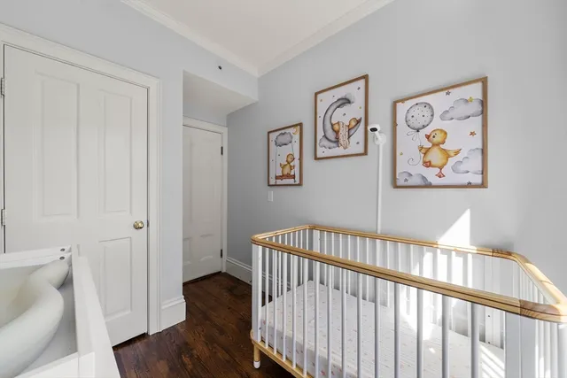 a view of a hallway with wooden floor and a bathroom