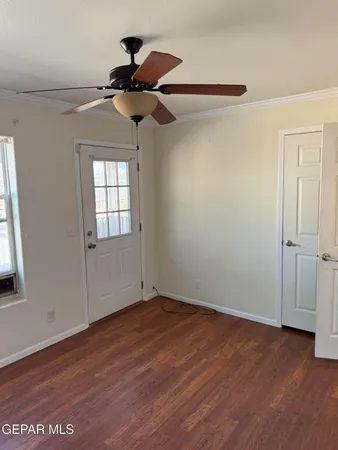 a view of empty room with wooden floor and fan