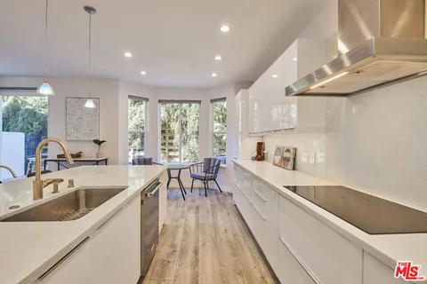 a kitchen with stainless steel appliances kitchen island granite countertop a sink and a refrigerator