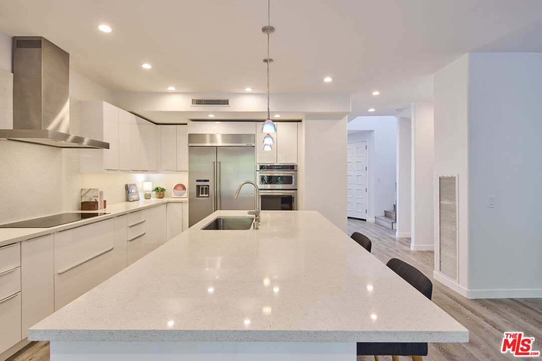 6465 Zuma View Place, Unit 163 Malibu, CA 90265 - Photo 9 of 26 a large white kitchen with wooden floor