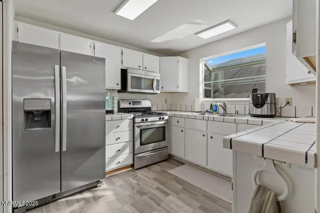a kitchen with white cabinets and stainless steel appliances