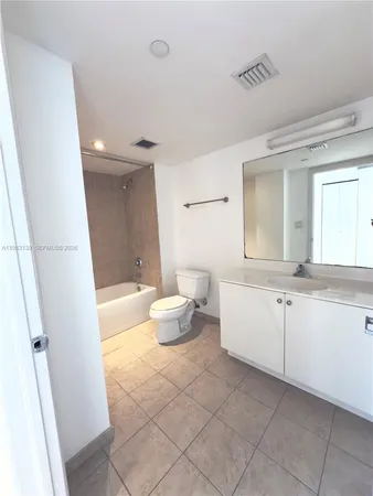 a spacious bathroom with a double vanity sink a toilet and a mirror