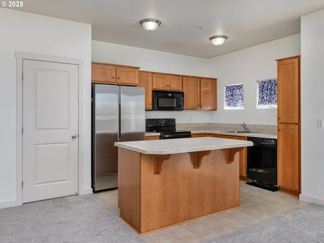 a view of kitchen with stainless steel appliances granite countertop a stove and a refrigerator
