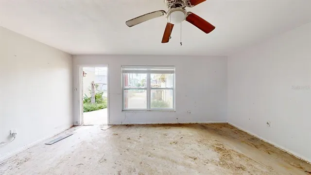 an empty room with a ceiling fan and window