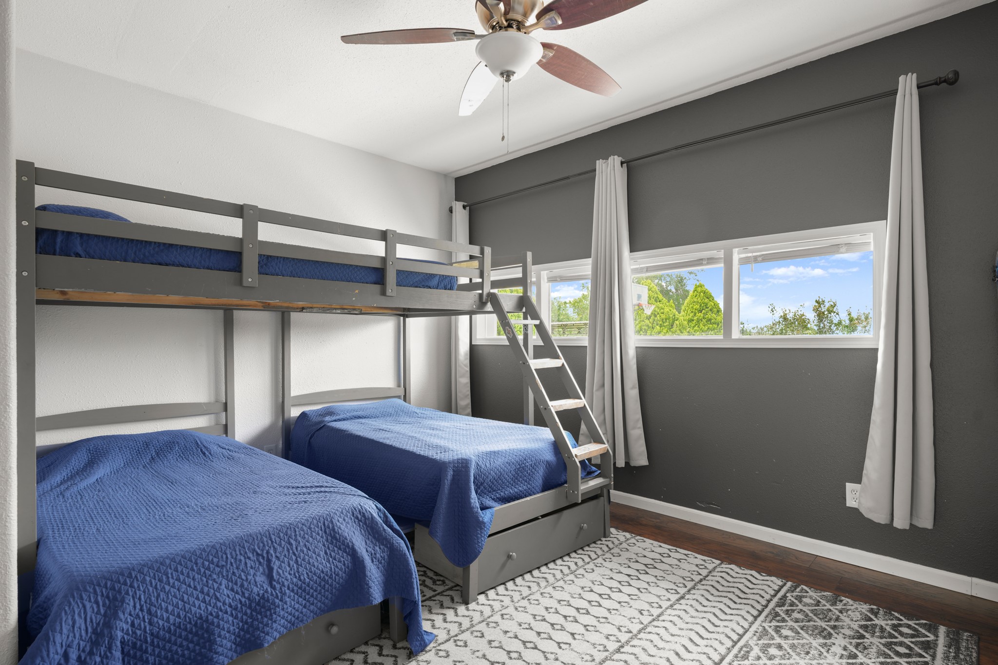 9725 Bock Road Buda, TX 78610 - Photo 12 of 32 A cheerful children's bedroom featuring a bunk bed, hardwood flooring, and bright windows.