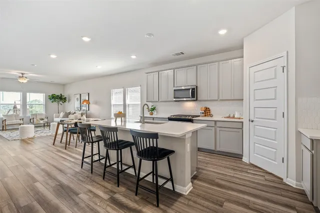 a living room with furniture large window and wooden floor