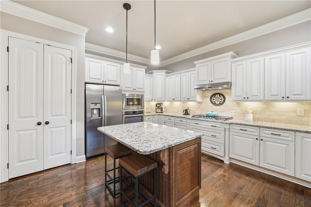 262 Trecastle Square Canton, GA 30114 - Photo 14 of 46 a kitchen with stainless steel appliances granite countertop a stove a sink dishwasher a refrigerator and white cabinets with wooden floor