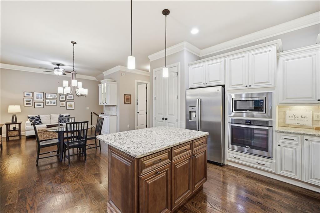 262 Trecastle Square Canton, GA 30114 - Photo 17 of 46 a kitchen with a refrigerator a stove a kitchen island a dining table and chairs with wooden floor