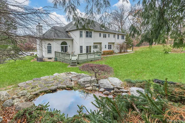 a view of a white house next to a yard with big trees