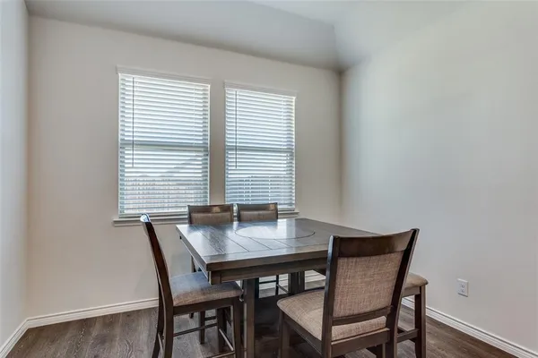 a kitchen with stainless steel appliances a table chairs refrigerator and microwave