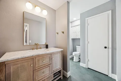 a bathroom with a granite countertop toilet a sink and a mirror