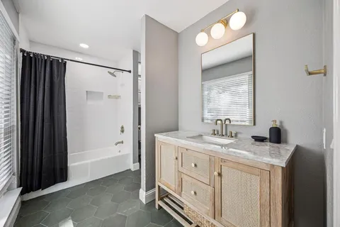 a spacious bathroom with a granite countertop sink mirror and a bathtub