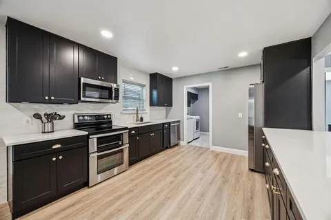 a large kitchen with stainless steel appliances granite countertop a stove refrigerator and microwave