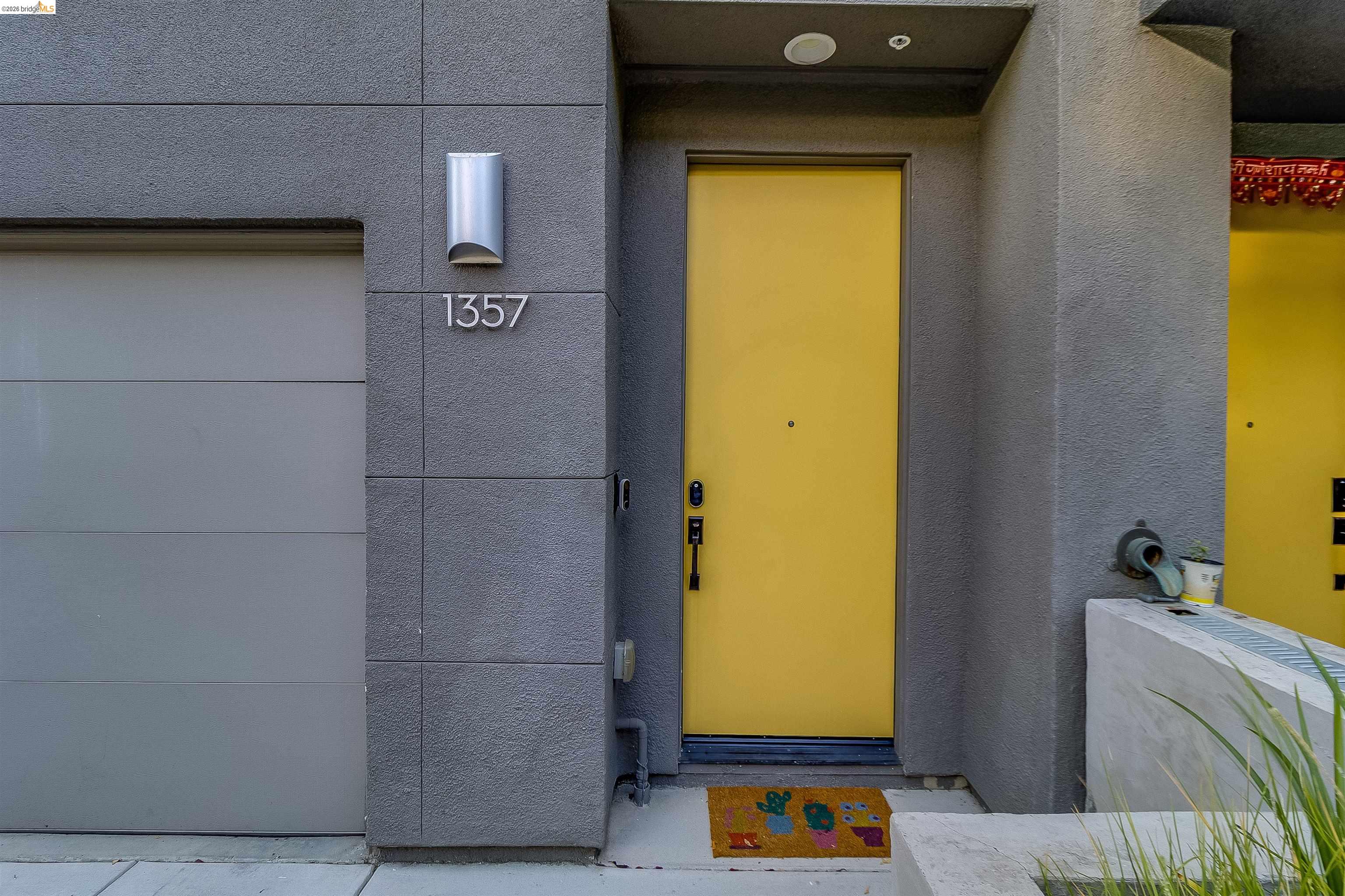 1357 Pullman Way Oakland, CA 94607 - Photo 3 of 37 Modern exterior featuring a bright yellow entry door, a gray paneled garage door, and a sleek wall sconce