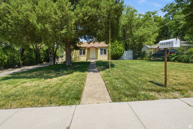 94 West 2000th Street North Clearfield, UT 84015 - Photo 16 of 26 Wide front exterior view with mature trees, walkway to the home, lawn space, and established neighborhood setting.