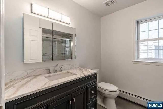 a bathroom with a granite countertop sink a toilet and a mirror