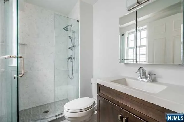 a bathroom with a sink a toilet a glass door a shower and a window