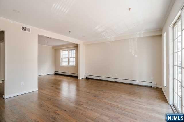 57 71st Street Guttenberg, NJ 07093 - Photo 4 of 18 an empty room with wooden floor and windows