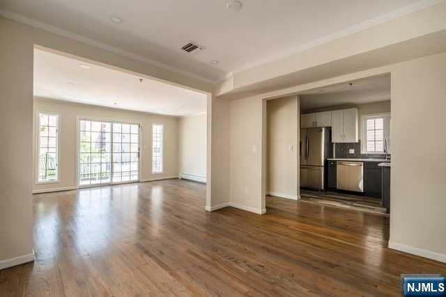 57 71st Street Guttenberg, NJ 07093 - Photo 5 of 18 a view of an empty room with wooden floor and a kitchen
