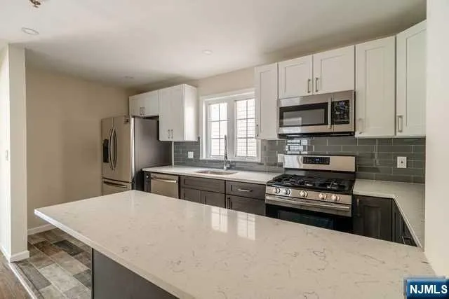 a kitchen with stainless steel appliances a stove a microwave a sink a refrigerator and cabinets