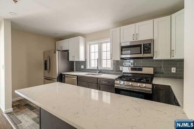 57 71st Street Guttenberg, NJ 07093 - Photo 6 of 18 a kitchen with stainless steel appliances a stove a microwave a sink a refrigerator and cabinets
