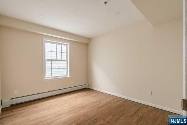 57 71st Street Guttenberg, NJ 07093 - Photo 9 of 18 an empty room with wooden floor and windows