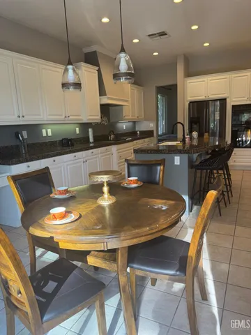 a kitchen with stainless steel appliances granite countertop a sink a stove a kitchen island with chairs and white cabinets