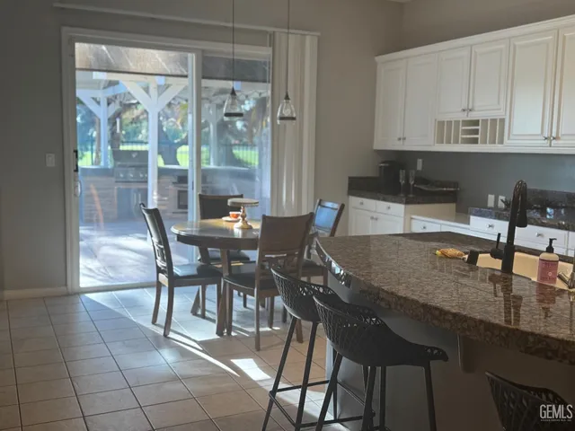 a kitchen with granite countertop a table chairs and wooden cabinets