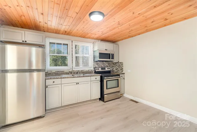 a kitchen with granite countertop a refrigerator stove and sink
