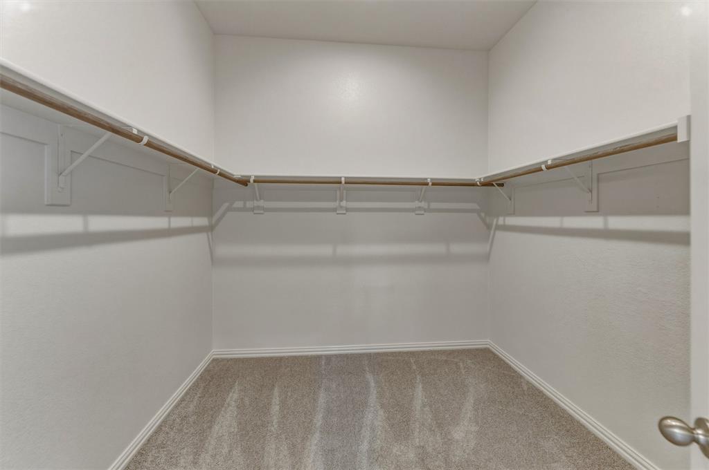 605 Tay Tay Way Springtown, TX 76082 - Photo 17 of 31 Walk-in closet featuring light gray carpeting, white walls, and built-in shelving with hanging rods