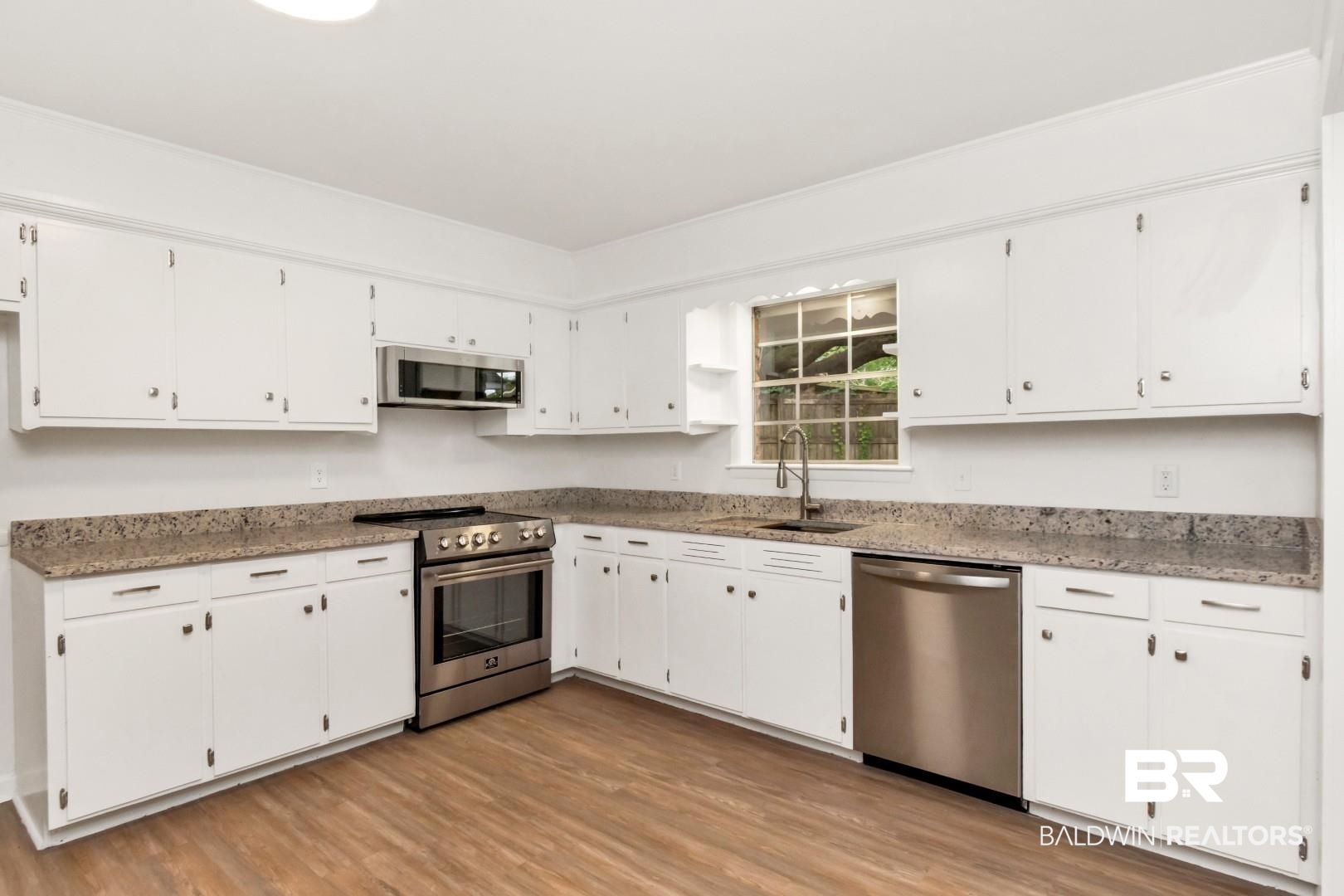 5217 Perin Road Mobile, AL 36693 - Photo 18 of 45 Kitchen featuring white cabinetry, speckled countertops, stainless steel appliances, wood-finish flooring, and a window above the sink