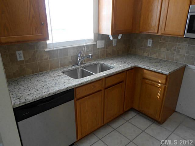 906 Treasure Place Southwest Concord, NC 28025 - Photo 5 of 15 a kitchen with granite countertop a sink and cabinets