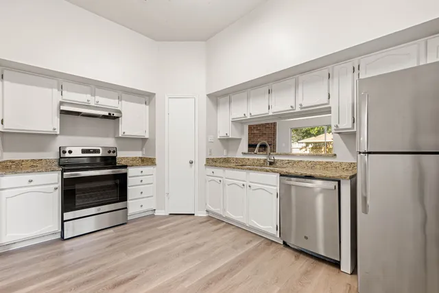 a kitchen with granite countertop a refrigerator stove and sink
