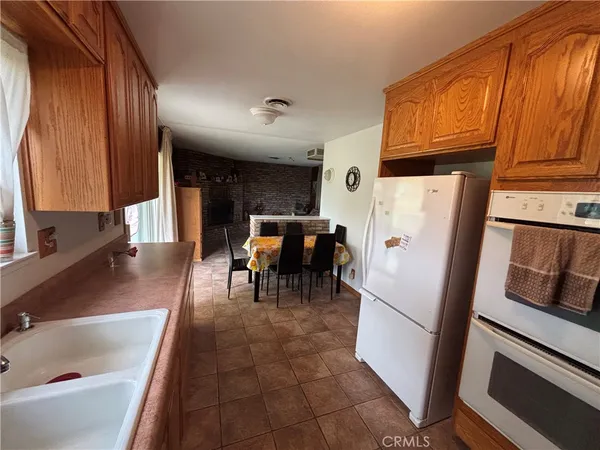 a kitchen with stainless steel appliances a refrigerator a stove a sink a dining table and chairs with wooden floor