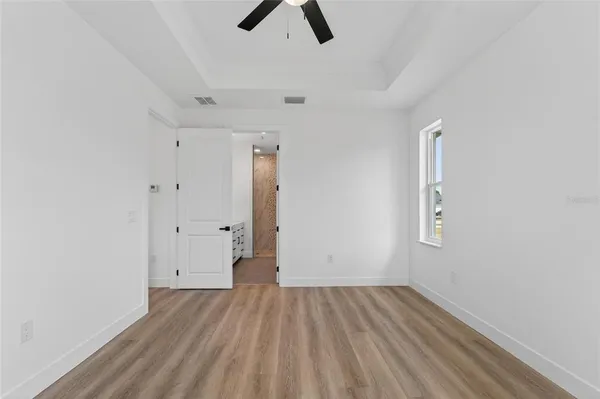 an empty room with chandelier fan and windows
