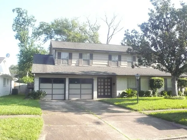 a front view of a house with a garden and trees