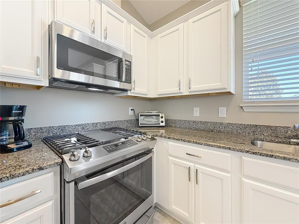 5647 Northwest 37th Lane Road Ocala, FL 34482 - Photo 5 of 50 a kitchen with granite countertop white cabinets and appliances