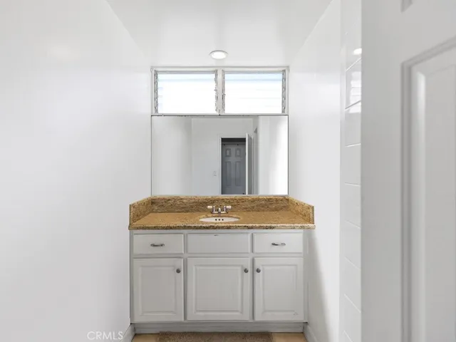 a bathroom with a granite countertop sink and white cabinets