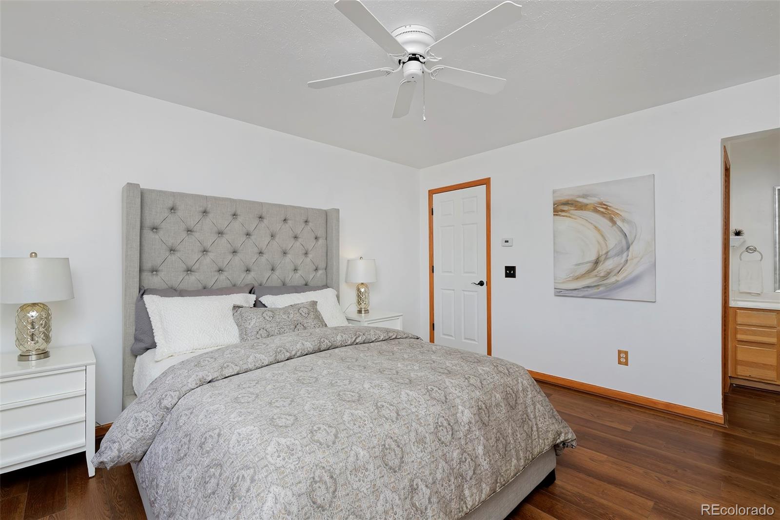 1340 Deerpath Trail Franktown, CO 80116 - Photo 20 of 44 a bedroom with a large bed and a chandelier fan