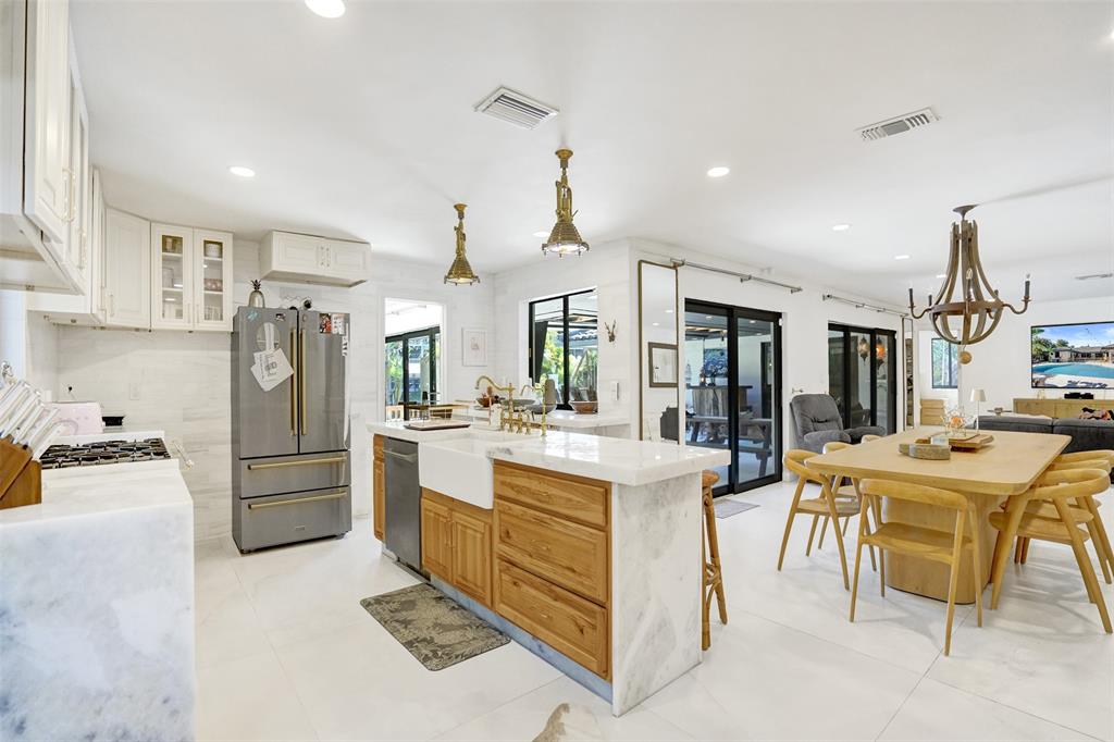 313 Layne Boulevard Hallandale Beach, FL 33009 - Photo 12 of 48 a kitchen with stainless steel appliances kitchen island granite countertop a refrigerator and a stove top oven