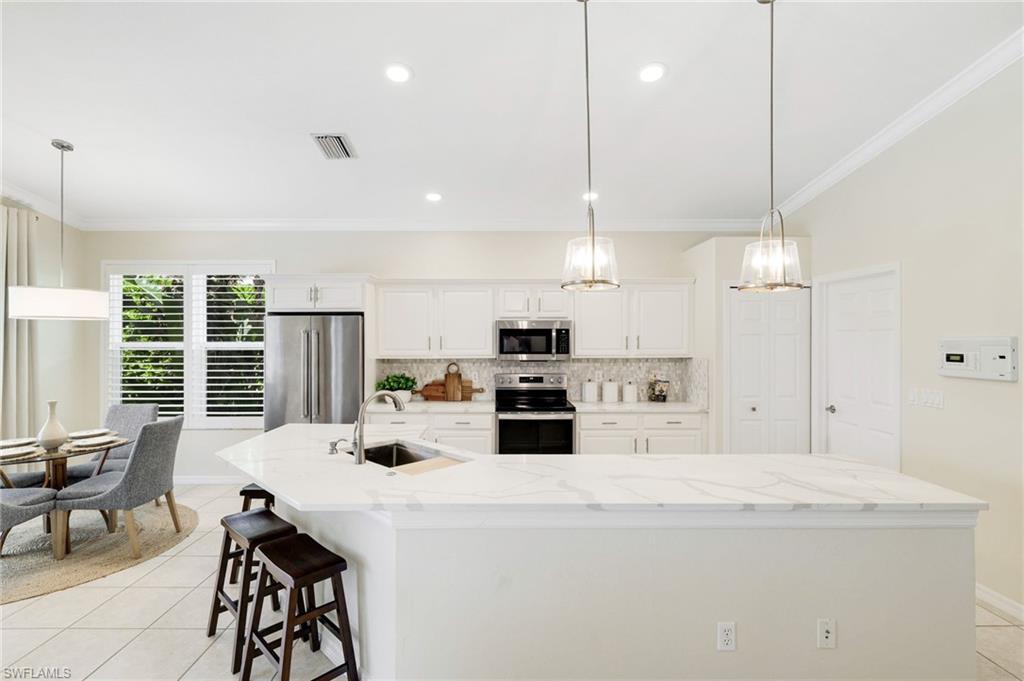 17897 Modena Road Miromar Lakes, FL 33913 - Photo 11 of 40 a kitchen with stainless steel appliances kitchen island a large island in the center