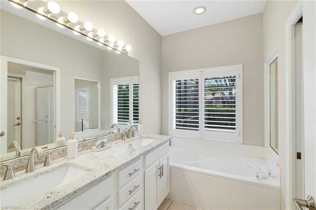 17897 Modena Road Miromar Lakes, FL 33913 - Photo 13 of 40 a bathroom with a granite countertop sink a large mirror and a bathtub with shower