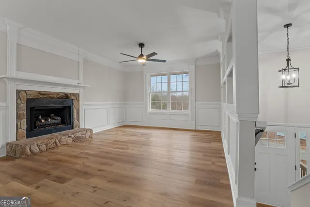 an empty room with wooden floor fireplace and windows