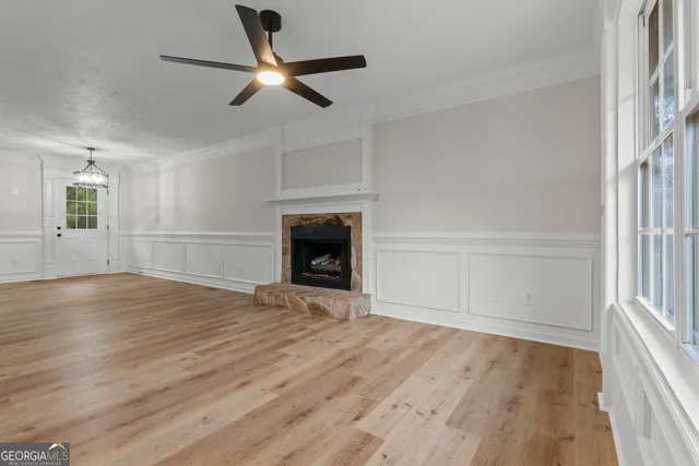 a view of an empty room with wooden floor fireplace and a window