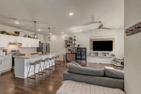 a living room with stainless steel appliances furniture a fireplace and a kitchen view