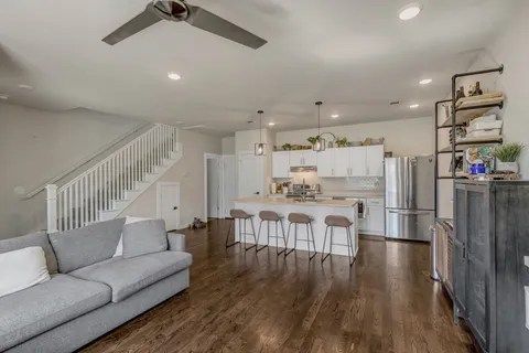 a living room with stainless steel appliances lots of furniture and wooden floors